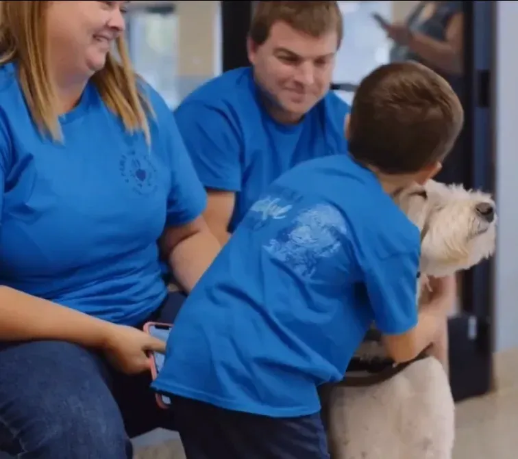 A boy hugging his new service dog as his family looks on